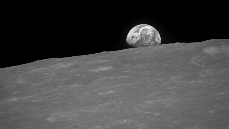 The Earth rising is about five degrees above the lunar horizon in this black and white telephoto view photographed from the Apollo 8 spacecraft near 110 degrees east longitude. The horizon, about 570 kilometers (350 statute miles) from the spacecraft, is near the eastern limb of the Moon as viewed from Earth. On Earth, 240,000 statute miles away, the sunset terminator crosses Africa. The South Pole is in the white area near the left end of the terminator. North and South America are under clouds.