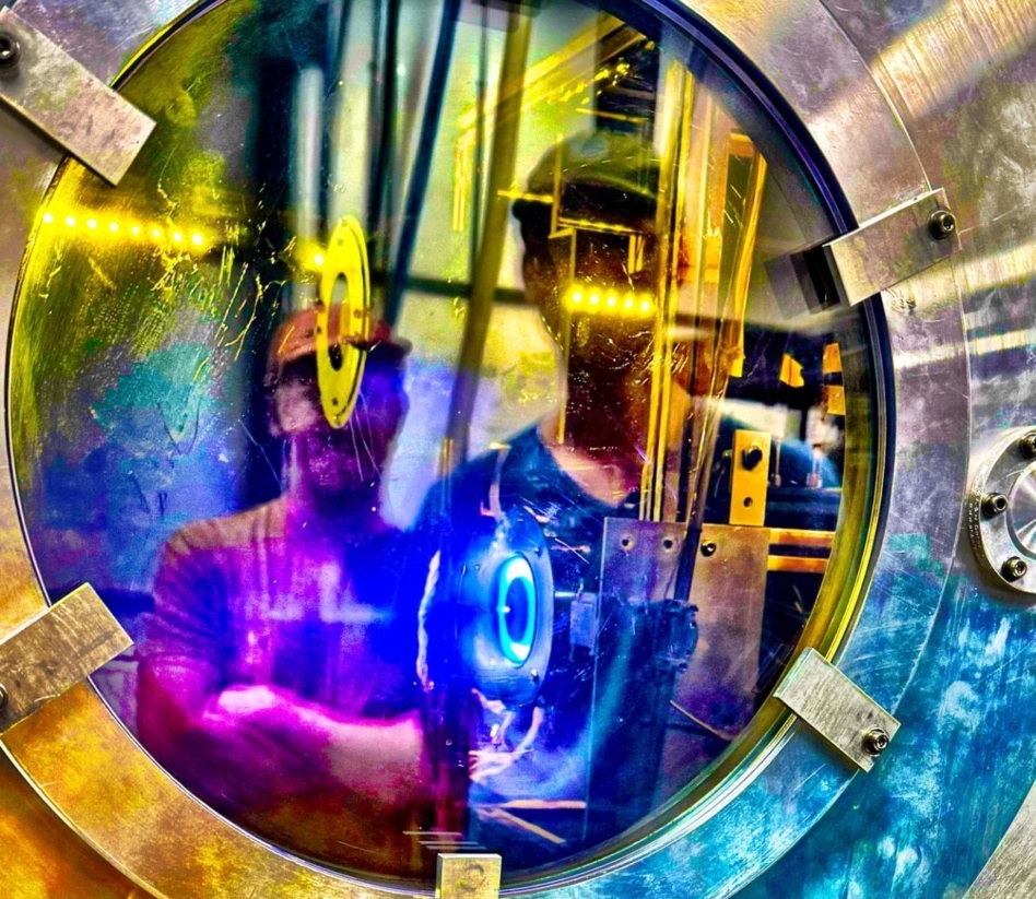 CisLunar engineer Steve Ward and Atomos Space propulsion manager Gavin Petit observe an electric thruster driven by a CisLunar PPU in a test chamber. Image: CisLunar Industries.